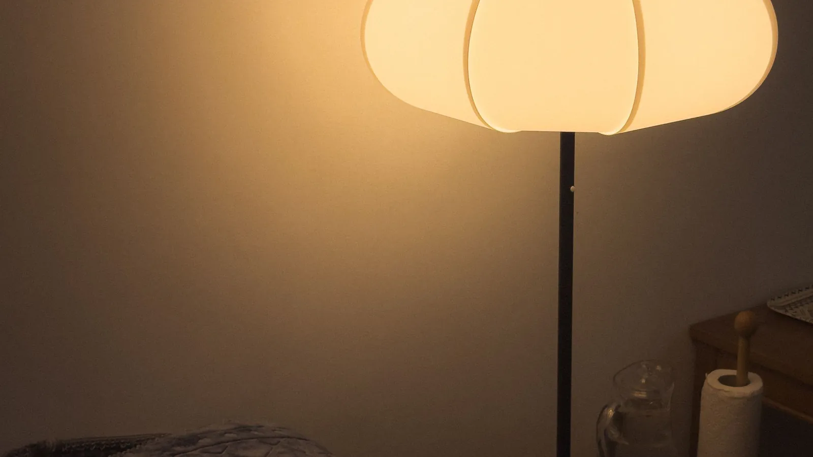 Living room at dusk lit by a warm paper floor lamp